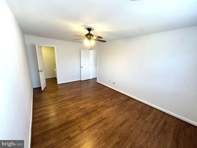 an empty room with wooden floor and chandelier fan