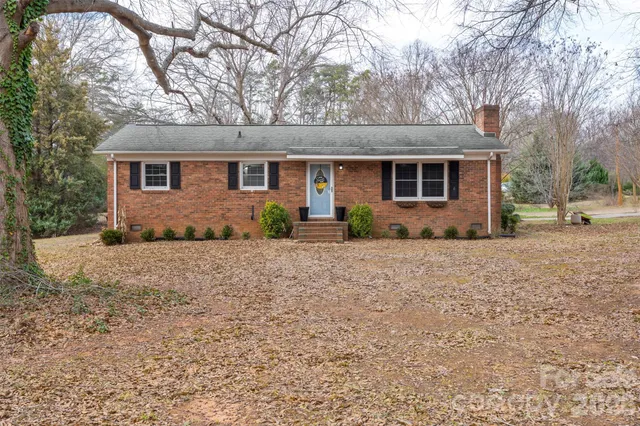 a front view of house with yard and trees in the background