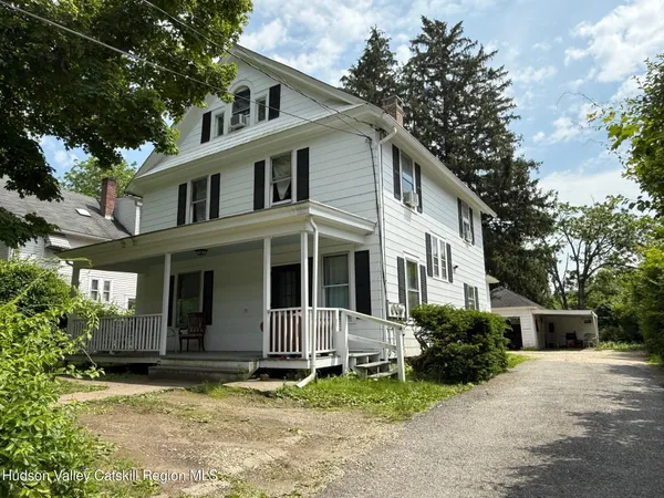 a white house that has a tree in front of it