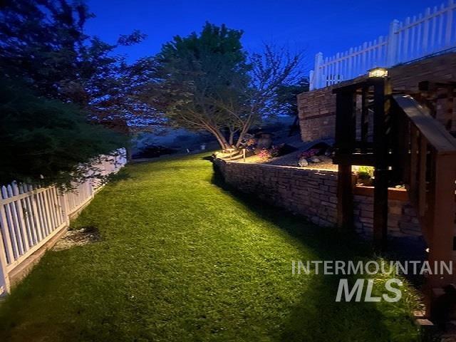 40 Bell Rapids Road Hagerman, ID 83332 - Photo 45 of 50 Expansive grass area featuring perimeter fencing, stone retaining walls, mature trees, and integrated landscape lighting