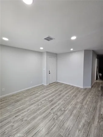 a view of an empty room with wooden floor and closet