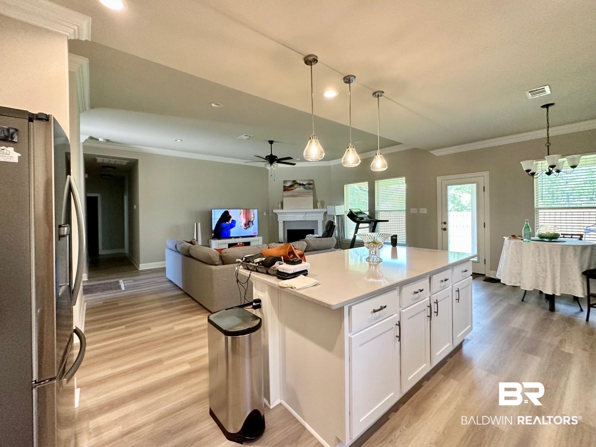 1009 Ruisseau Drive Foley, AL 36535 - Photo 18 of 55 Kitchen featuring a kitchen island, stainless steel fridge, decorative light fixtures, white cabinetry, and light hardwood / wood-style floors