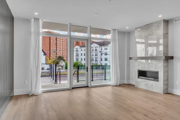 a view of an empty room with wooden floor and a fireplace