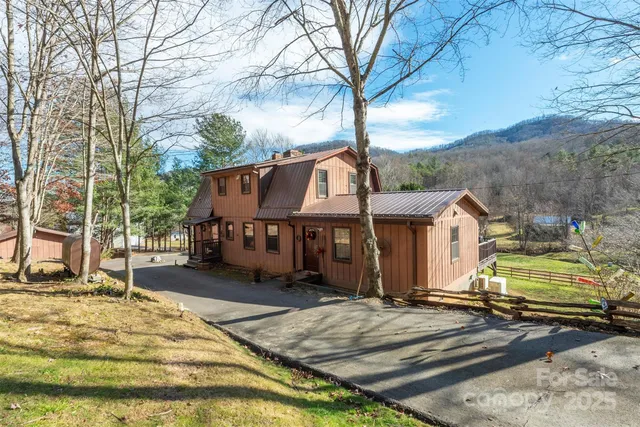 a view of a house with large trees and covered by wooden fence
