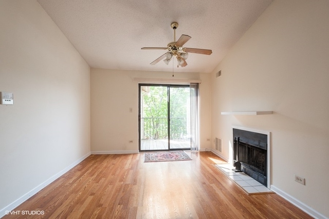 1905 North Hicks Road, Unit 205 Palatine, IL 60074 - Photo 4 of 10 an empty room with wooden floor fireplace and windows