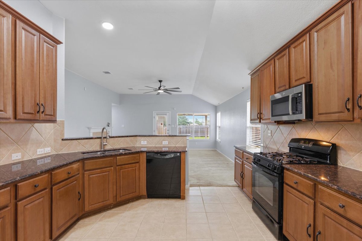 17812 Masi Loop Pflugerville, TX 78660 - Photo 13 of 38 Kitchen featuring wood cabinetry, dark countertops, tiled backsplash, and stainless steel microwave