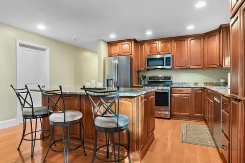 a kitchen with stainless steel appliances granite countertop a stove a sink a microwave a dining table and chairs