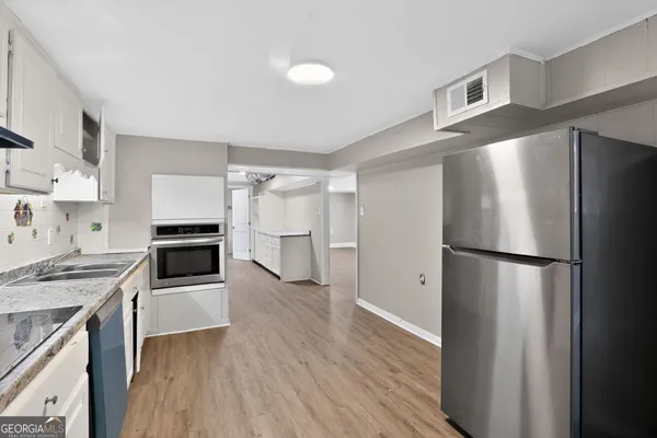 a kitchen with a refrigerator a stove top oven and cabinets