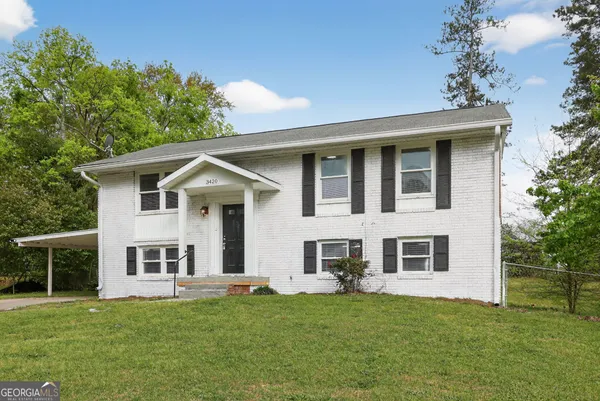 a view of a yard in front of a house with plants and large tree
