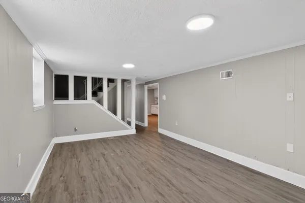an empty room with wooden floor and windows
