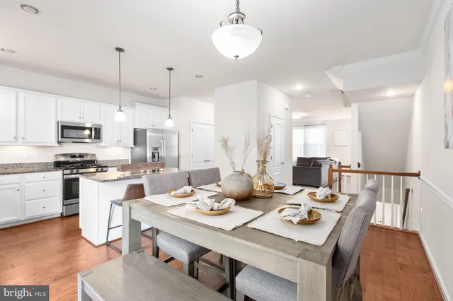 a kitchen with a stove a refrigerator a sink dishwasher a dining table and chairs with wooden floor