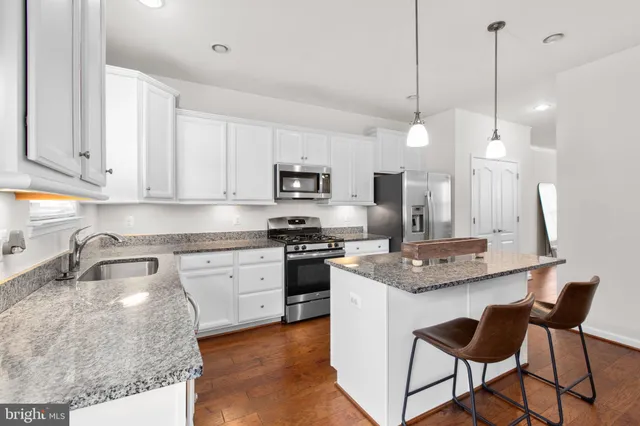 a kitchen with kitchen island granite countertop a stove a sink a center island a stove and a window