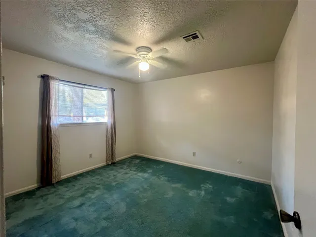 an empty room with window and ceiling fan