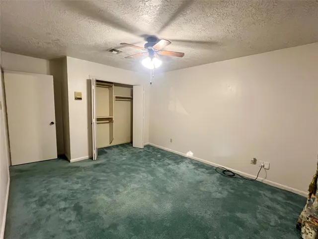 an empty room with closet and a chandelier fan