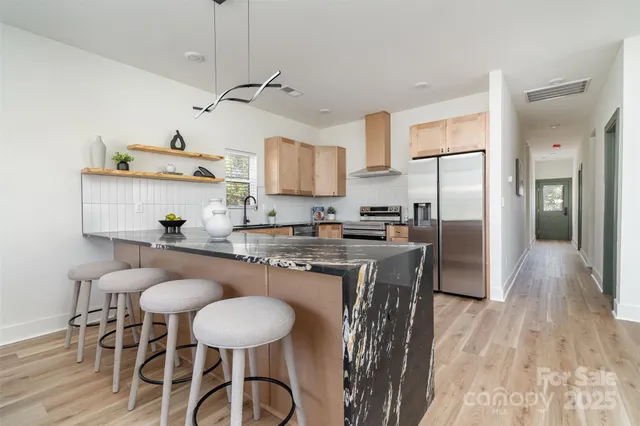 a kitchen with stainless steel appliances granite countertop a table chairs stove refrigerator and cabinets