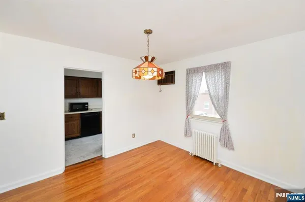a view of a kitchen and an empty room with wooden floor