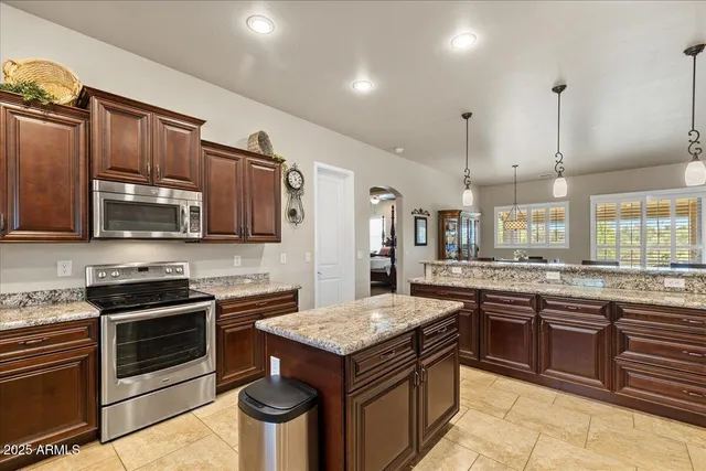 a kitchen with stainless steel appliances granite countertop a stove a sink dishwasher and a refrigerator with wooden cabinets