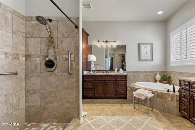 a bathroom with a granite countertop sink a mirror a bathtub and shower