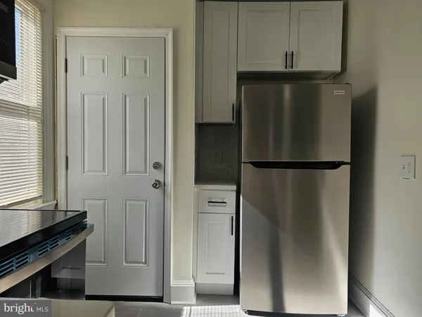 a view of a kitchen with refrigerator and wooden floor