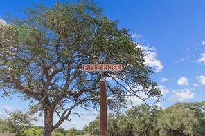 Lot 7 Rifle Ridge Burnet, TX 78611 - Photo 2 of 5 Mature trees frame the property marker under a vast blue sky.