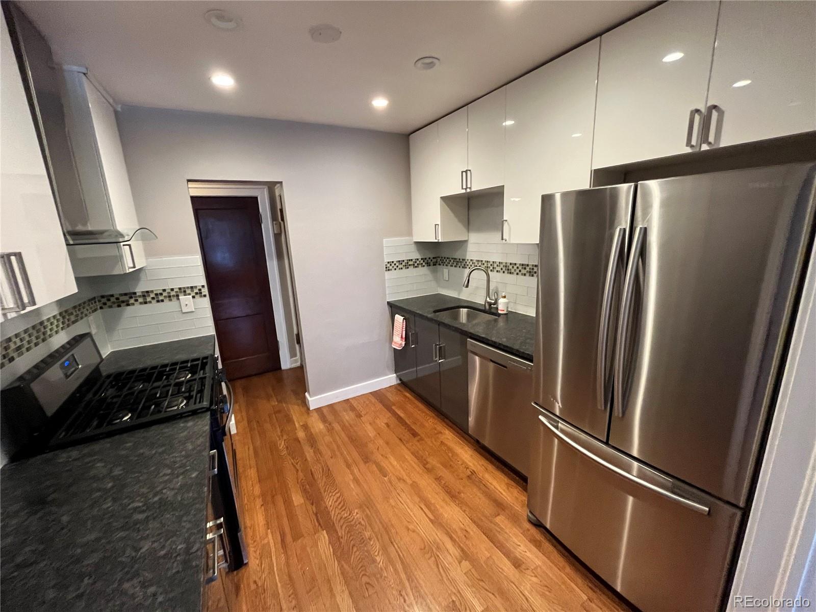 1684 Harrison Street, Unit 8 Denver, CO 80206 - Photo 11 of 21 a kitchen with stainless steel appliances a refrigerator a stove a sink and a refrigerator