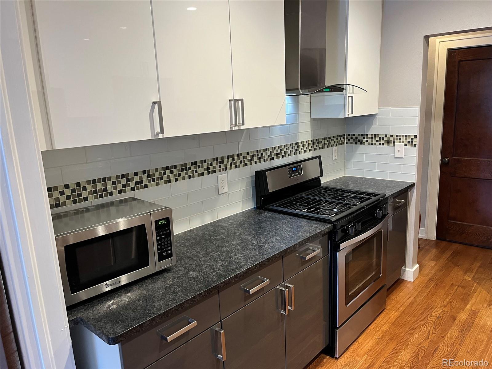 1684 Harrison Street, Unit 8 Denver, CO 80206 - Photo 8 of 21 a kitchen with granite countertop a stove microwave and sink