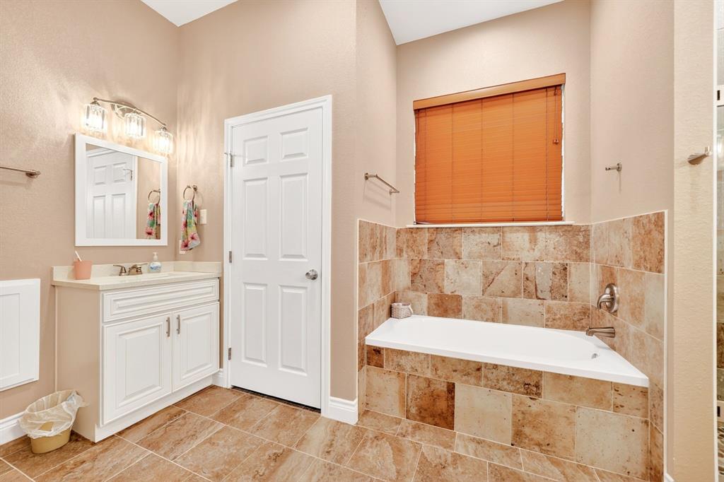 5230 Esquire Estates Road Mabank, TX 75156 - Photo 18 of 39 Bathroom featuring a corner soaking tub with tile surround, a single vanity with a white cabinet, and tile flooring