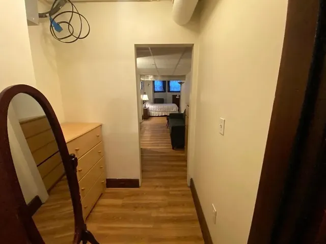 a view of a hallway with wooden floor and a bathroom