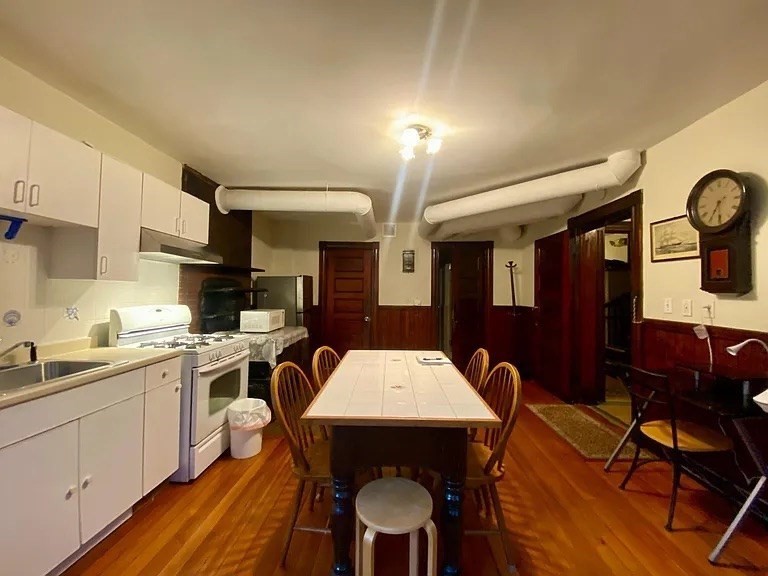 72 Bay State Road, Unit G Boston, MA 02215 - Photo 2 of 25 a kitchen with a dining table chairs and white cabinets