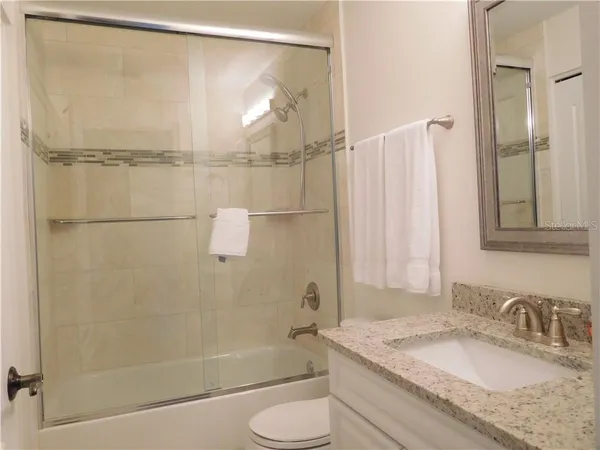 a bathroom with a granite countertop shower sink and toilet