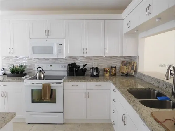 a kitchen with stainless steel appliances granite countertop a sink stove and white cabinets