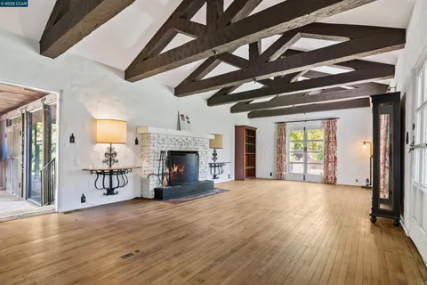 a view of an empty room with wooden floor fireplace and a window