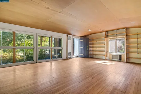 a view of empty room with wooden floor and floor to ceiling window