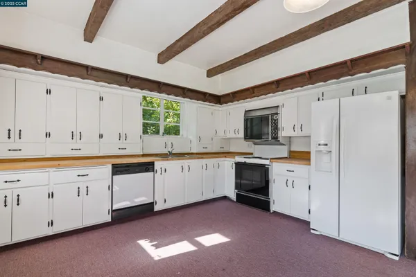 a kitchen with granite countertop white cabinets and white appliances