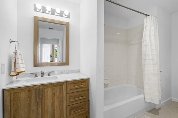 a bathroom with a granite countertop sink a mirror a shower and a bathtub