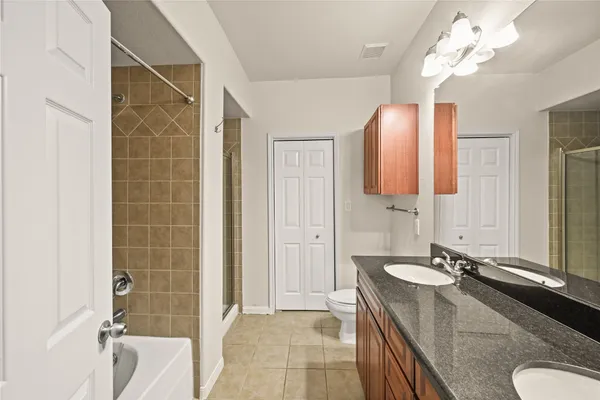 a bathroom with a granite countertop sink a toilet and shower