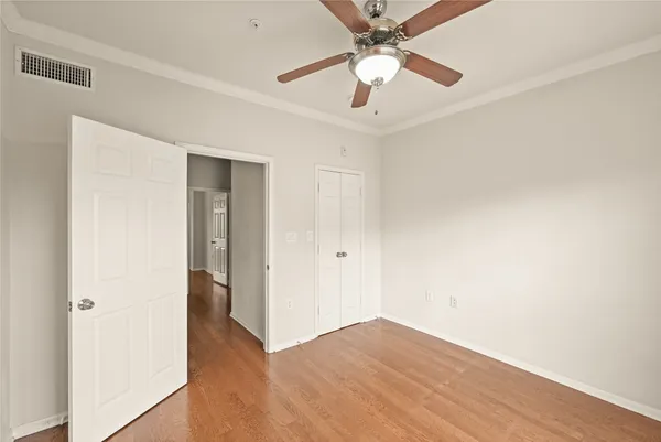 an empty room with wooden floor and ceiling fan