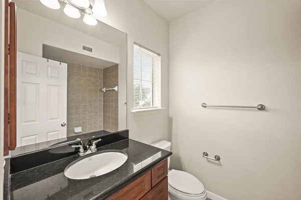 a bathroom with a granite countertop sink toilet a mirror and shower