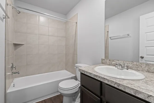 a bathroom with a granite countertop sink a toilet a mirror a bathtub and shower