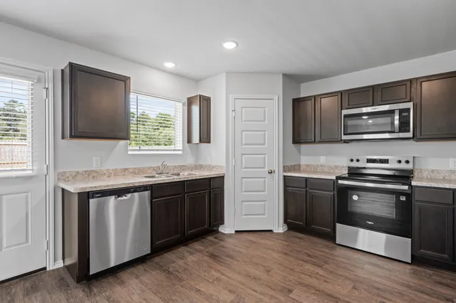 a kitchen with stainless steel appliances granite countertop a stove a sink and a microwave