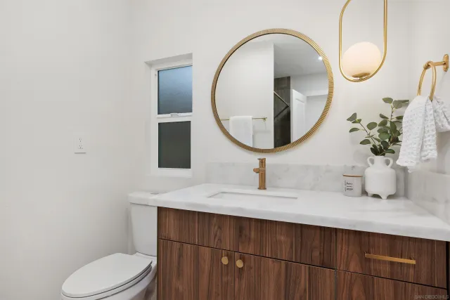 a bathroom with a granite countertop toilet sink mirror and vanity