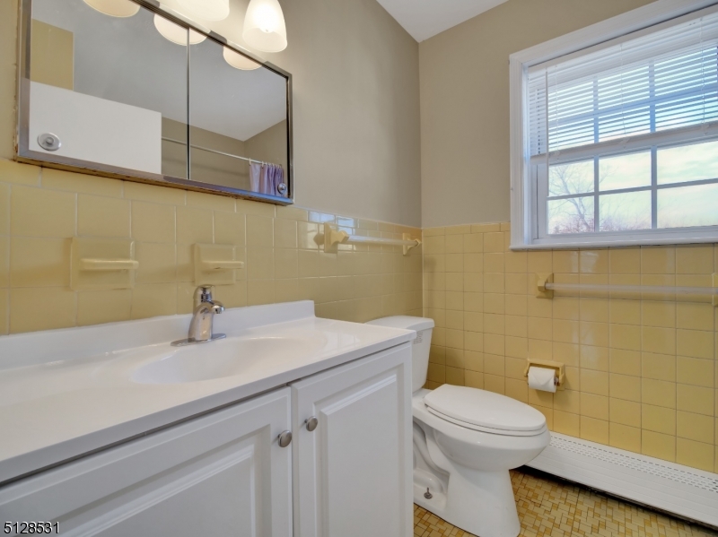 153 Ridge Road, Unit D Cedar Grove, NJ 07009 - Photo 14 of 21 a bathroom with a sink a toilet and mirror