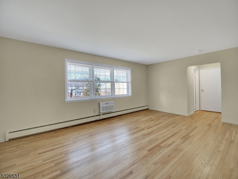 153 Ridge Road, Unit D Cedar Grove, NJ 07009 - Photo 7 of 21 an empty room with wooden floor and windows