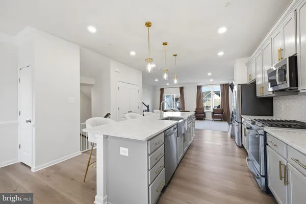 a large kitchen with kitchen island a island a stove a refrigerator a dining table and chairs with wooden floor