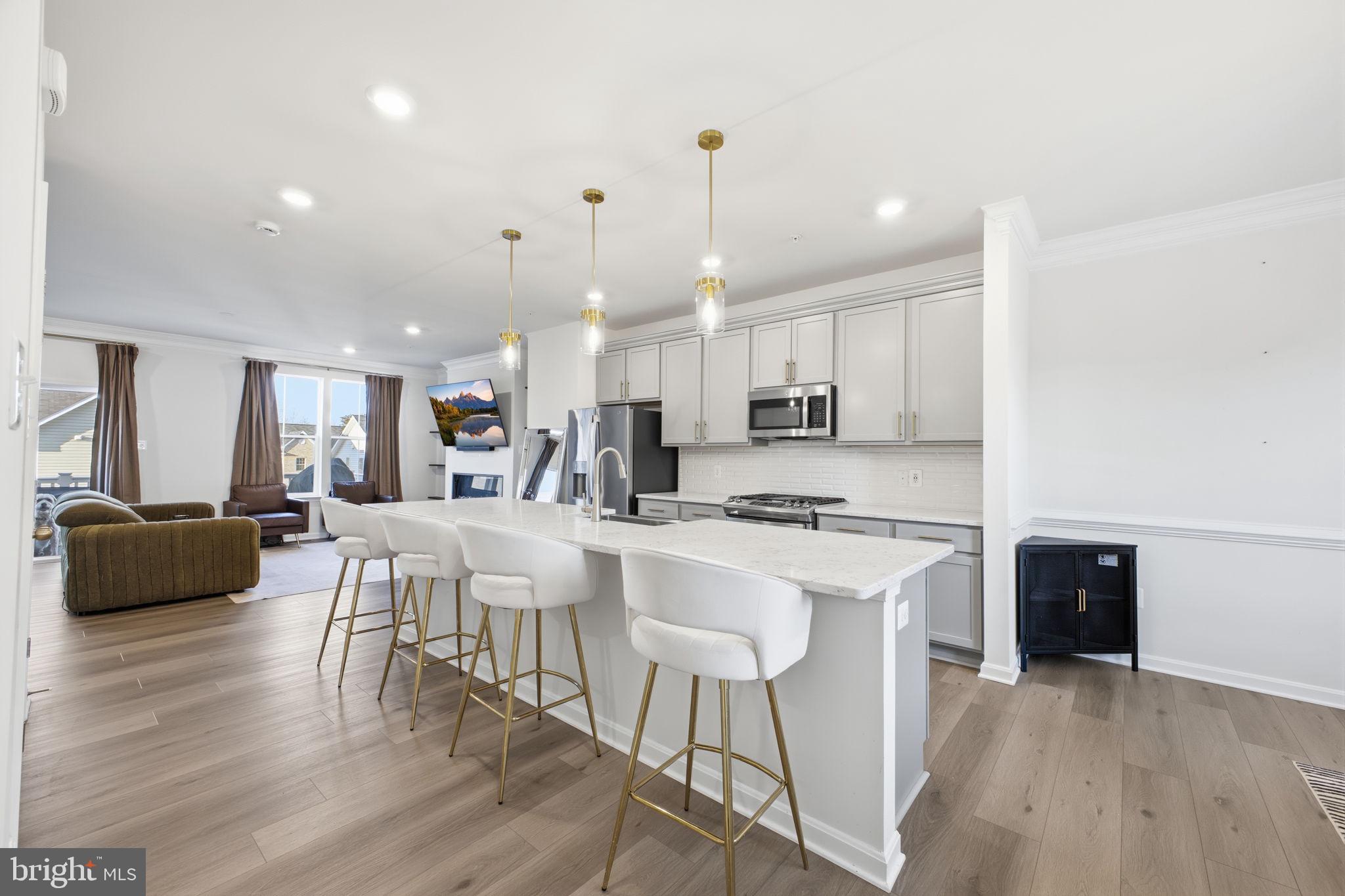217 Southwind Drive Accokeek, MD 20607 - Photo 8 of 34 a large kitchen with kitchen island a island a stove a refrigerator a dining table and chairs with wooden floor
