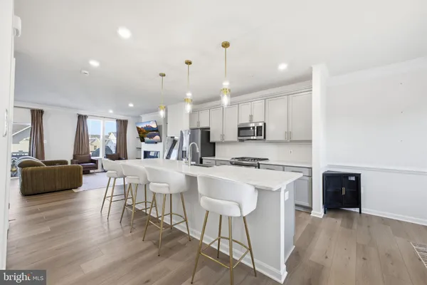 a kitchen with stainless steel appliances a refrigerator a stove a sink a dining table and chairs with wooden floor
