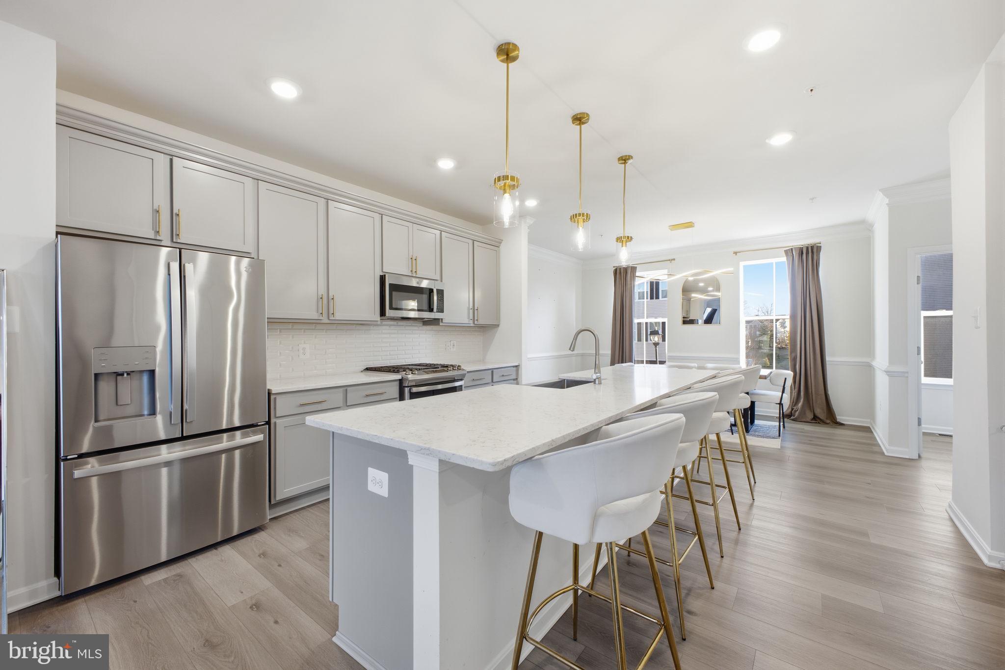 217 Southwind Drive Accokeek, MD 20607 - Photo 9 of 34 a kitchen with stainless steel appliances a refrigerator a stove a sink a dining table and chairs with wooden floor