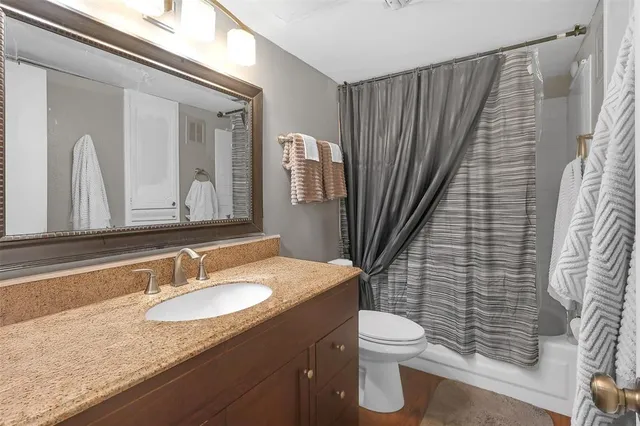 a bathroom with a granite countertop sink toilet and shower
