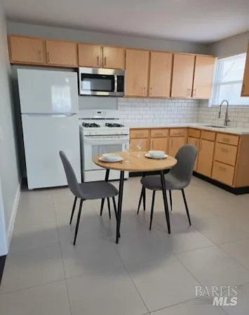 a kitchen with stainless steel appliances kitchen island granite countertop a table chairs sink and cabinets