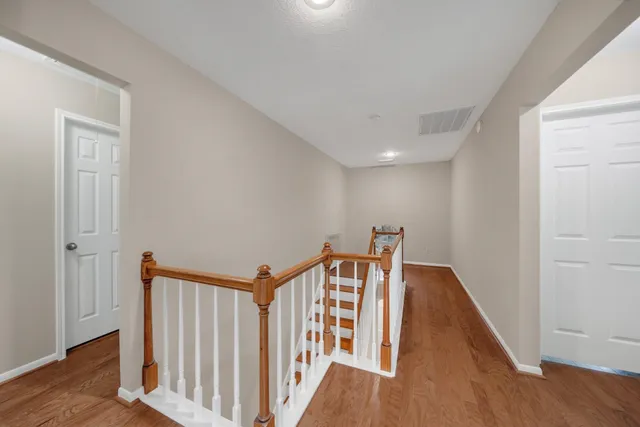a view of a hallway with wooden floor and stairs